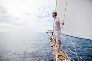 Mann in Segelboot auf offenem Meer