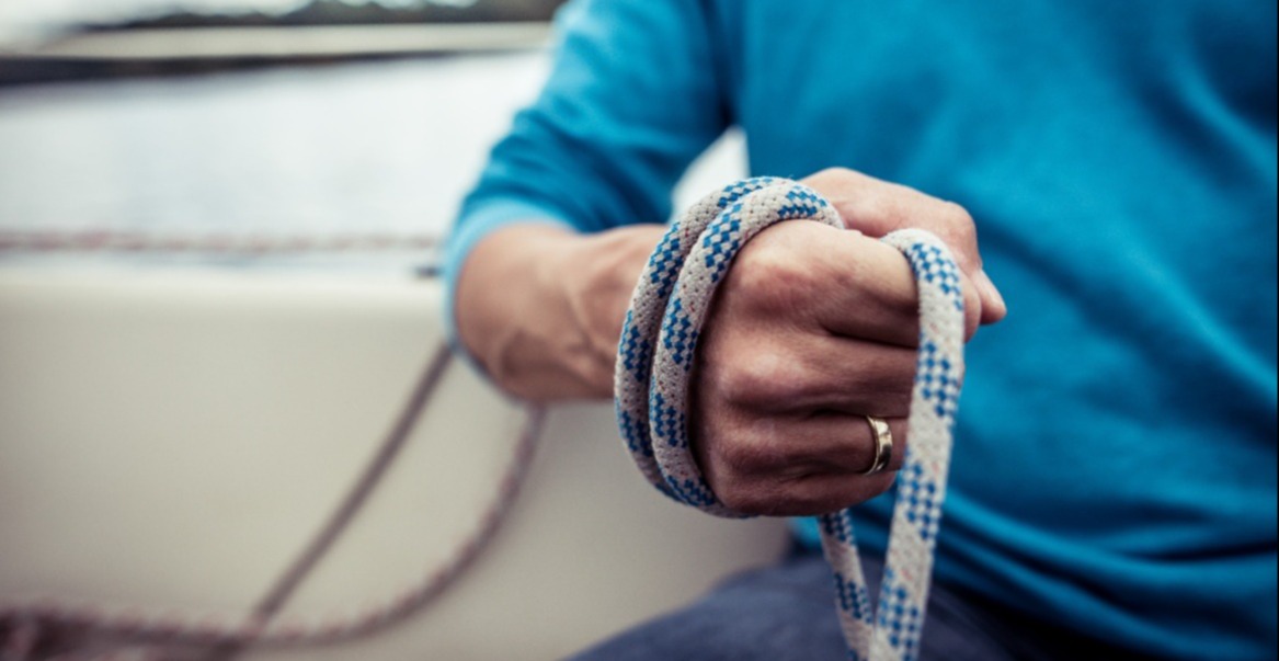 Hand mit Seil blauer Pullover