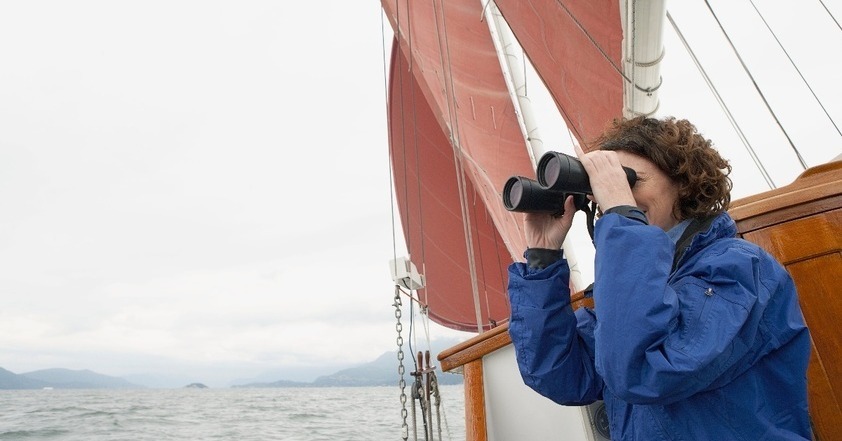 Frau mit Fernglas auf offenem Meer symbolisiert Prüfung Einkauf in die Pensionskasse und Steuern Sparen